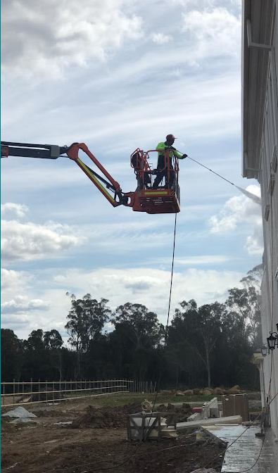 Clinical Blast technician cleaning a building façade from an elevated boom lift